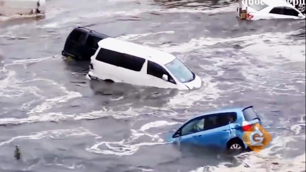 cars being moved in muddy water caused by a tsunami