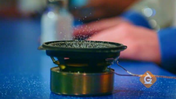 particles of salt bounce on top of a speaker