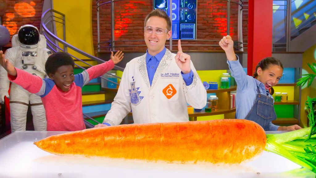 scientist and kids pose next to a very large carrot
