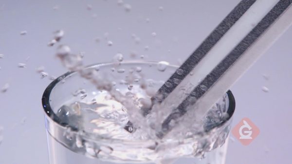 tuning fork vibrations make water splash out of the glass